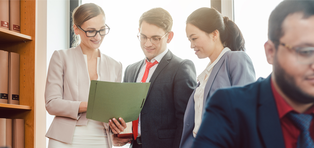 Trois avocats d’un service juridique interne discutent en regardant des documents.