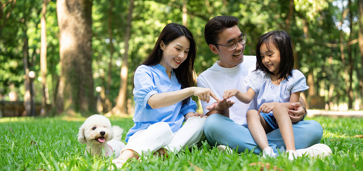 Photo d’une jeune famille asiatique au parc avec leur petit chien.