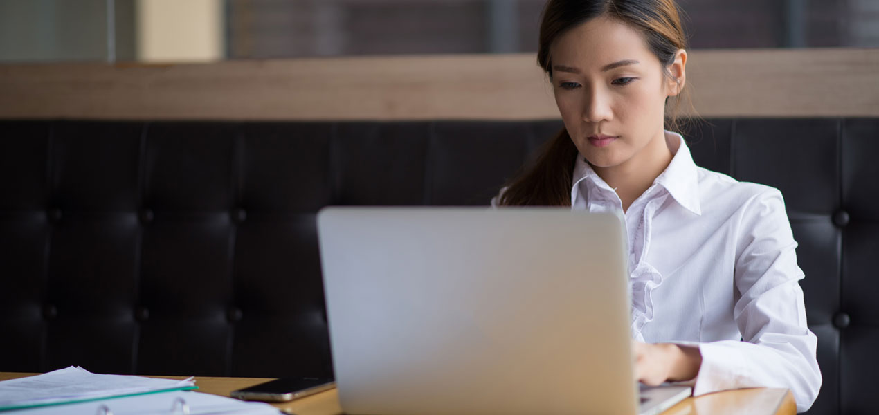 Une jeune femme d’affaires asiatique dans un café avec son ordinateur portable.