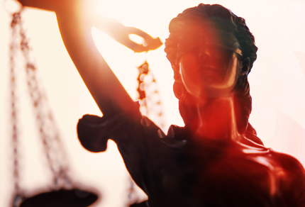 Gros plan d'une statue de la justice avec un rayon de soleil en arrière-plan