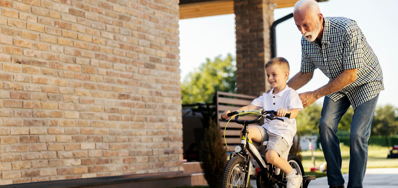 Un homme âgé et un jeune garçon font du vélo ensemble, profitant de leur temps à l’extérieur.