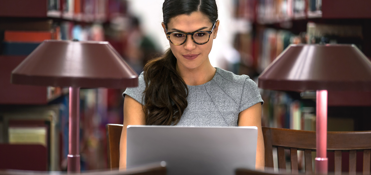 Un étudiant universitaire étudiant sur un ordinateur portable dans une bibliothèque