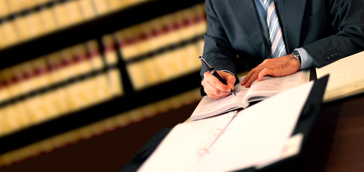 Un avocat prend des notes en examinant des documents.