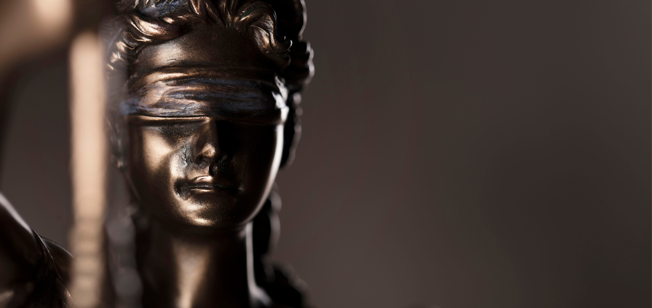 Gros plan sur une statue de Justice en bronze.