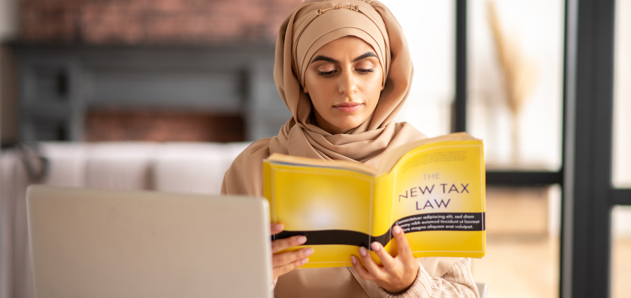 Une femme musulmane lisant un livre sur le droit fiscal