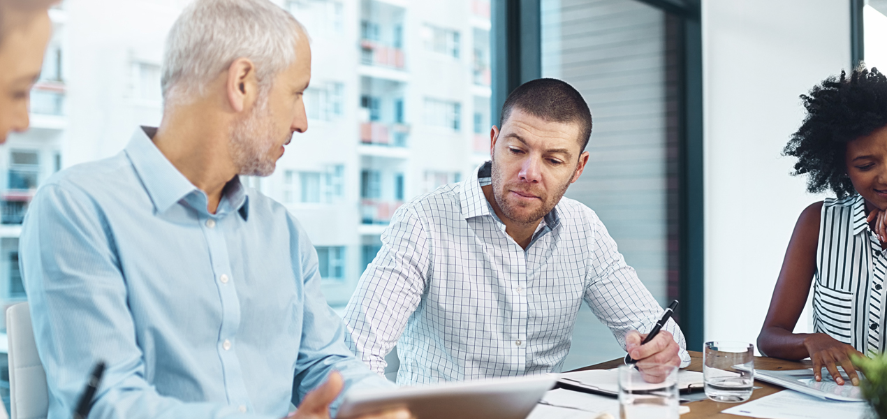 Quatre personnes sont assises autour d’une table dans un bureau moderne, en pleine réunion.