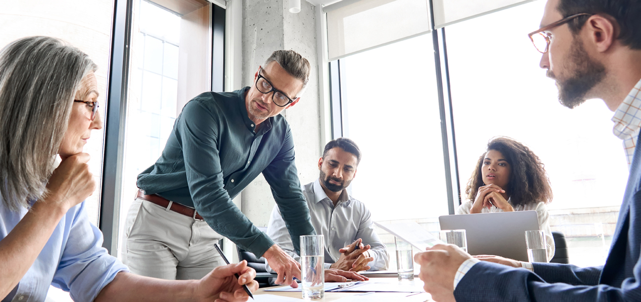 Réunion de cinq personnes discutant de certains documents.